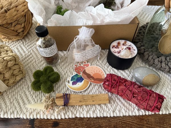 Everything inside smudge kit laid out: intention candle, palo santo bundle, palm stone, sage bundle, intention herb jar, himalayan salt bundle and other accessories